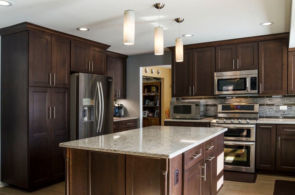 Open concept kitchen - mid-sized transitional l-shaped porcelain tile open concept kitchen idea in Chicago with an undermount sink, raised-panel cabinets, dark wood cabinets, quartz countertops, beige backsplash, stainless steel appliances and blue walls