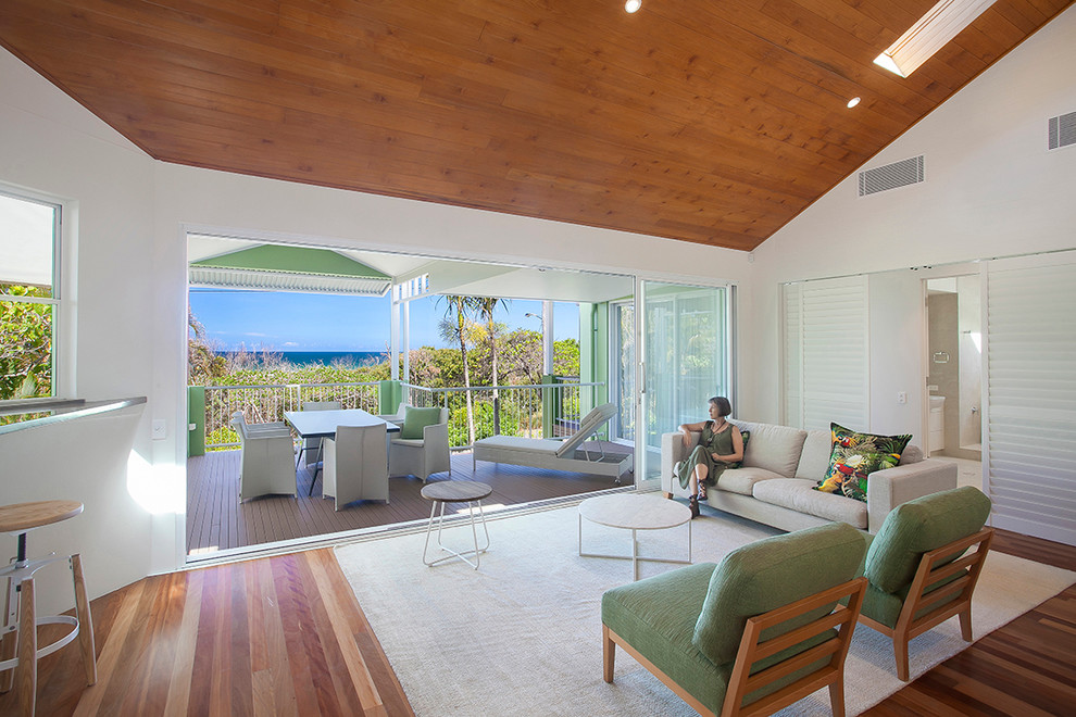 Large beach style open concept living room in Sunshine Coast with white walls, medium hardwood floors, a corner fireplace, a wood fireplace surround and no tv.