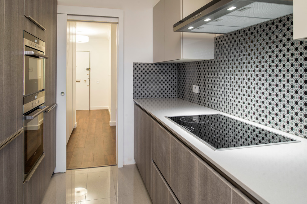 This is an example of a small contemporary u-shaped separate kitchen in London with flat-panel cabinets, grey cabinets, quartz benchtops, grey splashback, ceramic splashback, black appliances, ceramic floors and no island.