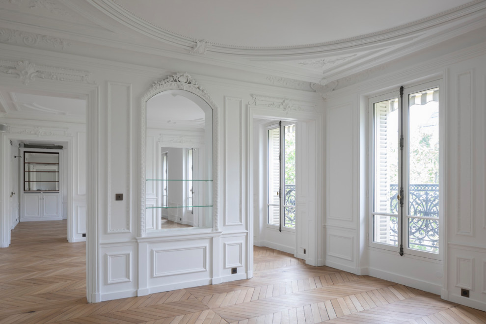 Идея дизайна: большая открытая гостиная комната в стиле неоклассика (современная классика) с белыми стенами, светлым паркетным полом, стандартным камином, фасадом камина из кирпича, бежевым полом и панелями на стенах