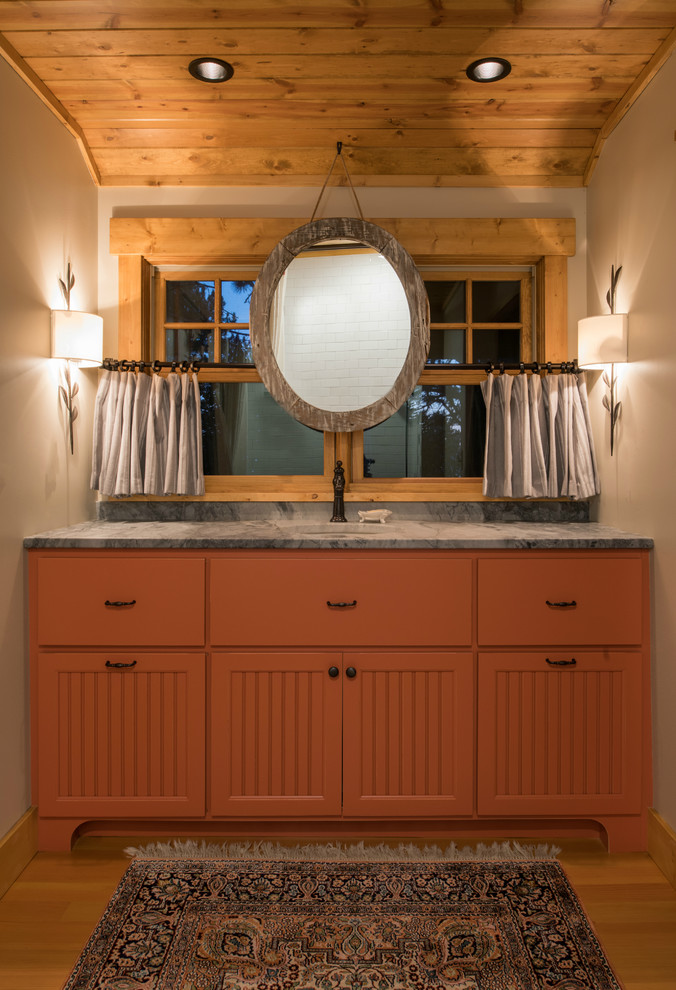 Mid-sized country 3/4 bathroom in Minneapolis with beaded inset cabinets, orange cabinets, a two-piece toilet, beige walls, light hardwood floors, an undermount sink, granite benchtops and brown floor.
