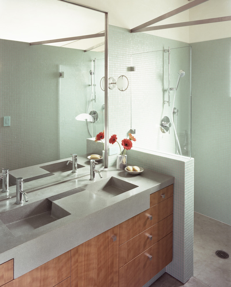 This is an example of a mid-sized beach style 3/4 bathroom in San Francisco with flat-panel cabinets, medium wood cabinets, a curbless shower, green tile, ceramic tile, an integrated sink, a one-piece toilet, white walls and concrete floors.