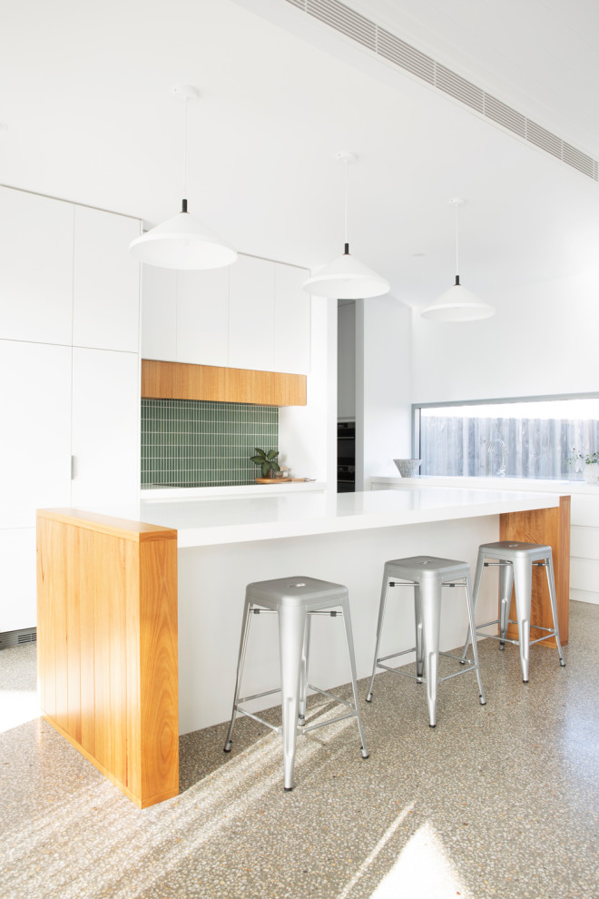 Design ideas for a mid-sized modern l-shaped open plan kitchen in Melbourne with flat-panel cabinets, white cabinets, green splashback, with island, grey floor, white benchtop, an undermount sink, quartz benchtops, ceramic splashback, panelled appliances and concrete floors.