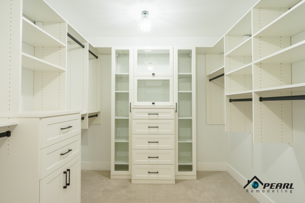 This is an example of a large modern gender-neutral walk-in wardrobe in Los Angeles with shaker cabinets, white cabinets, carpet and beige floor.
