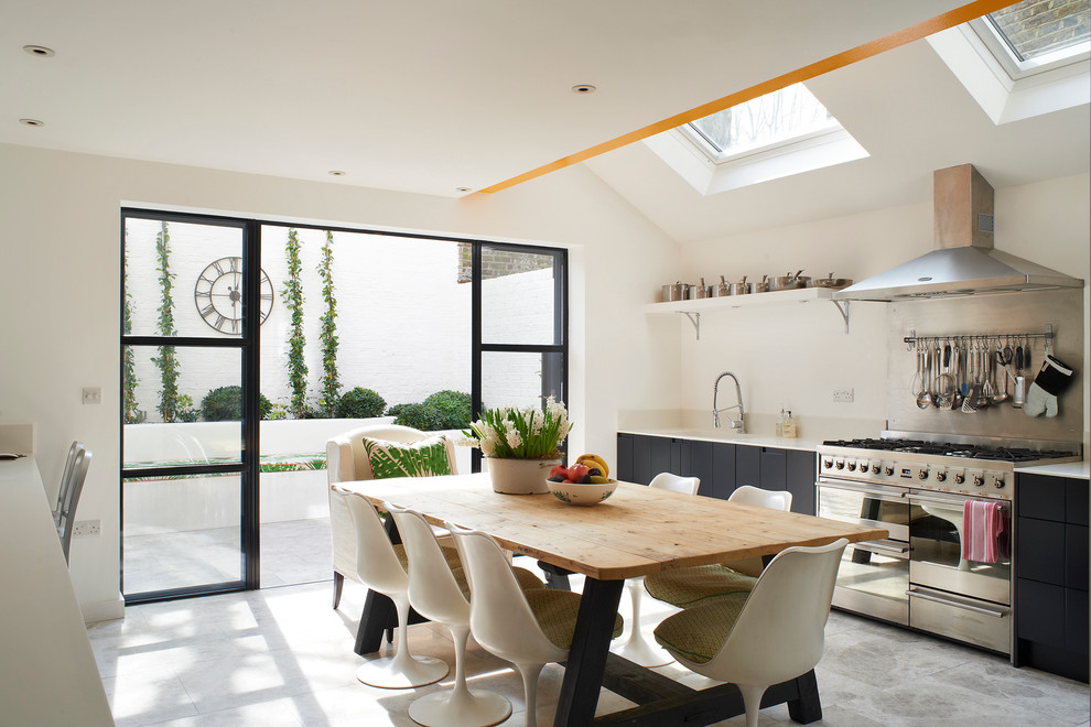 Photo of an eclectic eat-in kitchen in London with flat-panel cabinets and black cabinets.