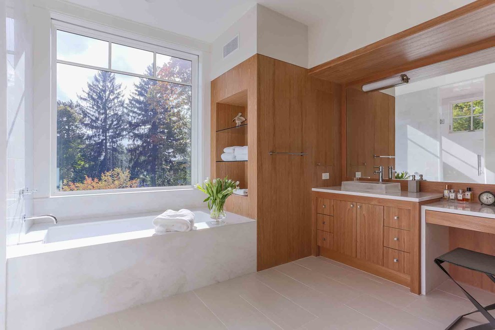 Large modern master bathroom in Boston with flat-panel cabinets, medium wood cabinets, an alcove tub, an alcove shower, a wall-mount toilet, white tile, marble, white walls, ceramic floors, a trough sink, quartzite benchtops, grey floor, a hinged shower door and white benchtops.