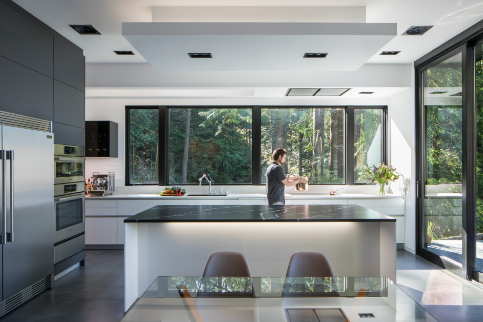 Photo of a large contemporary l-shaped open plan kitchen in Seattle with a double-bowl sink, flat-panel cabinets, grey cabinets, quartz benchtops, white splashback, engineered quartz splashback, stainless steel appliances, concrete floors, with island, grey floor, white benchtop and vaulted.