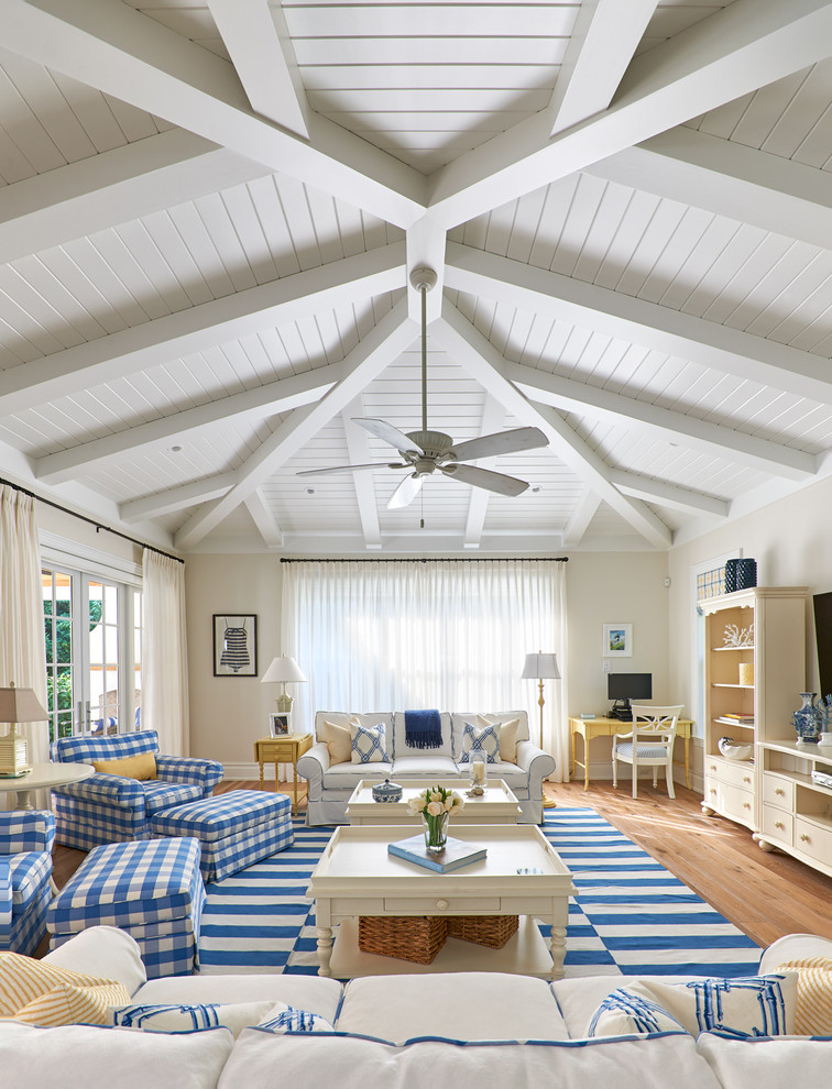 Inspiration for a large beach style family room in Miami with beige walls, a wall-mounted tv and medium hardwood floors.