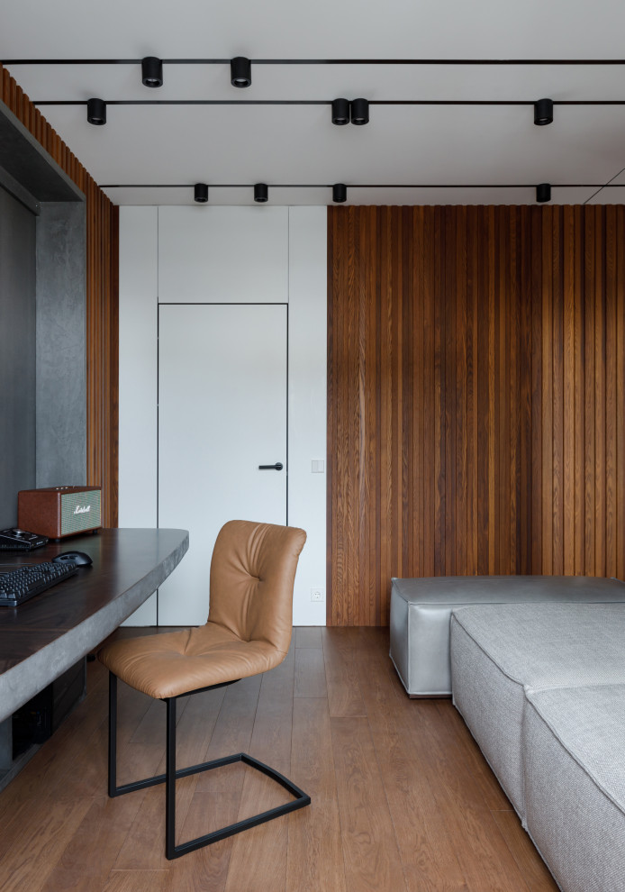 На фото: рабочее место среднего размера в современном стиле с серыми стенами, темным паркетным полом, встроенным рабочим столом, коричневым полом и деревянными стенами с