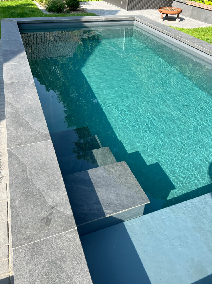 Kleiner Moderner Schwimmteich hinter dem Haus in rechteckiger Form mit Pool-Gartenbau und Natursteinplatten in Hamburg