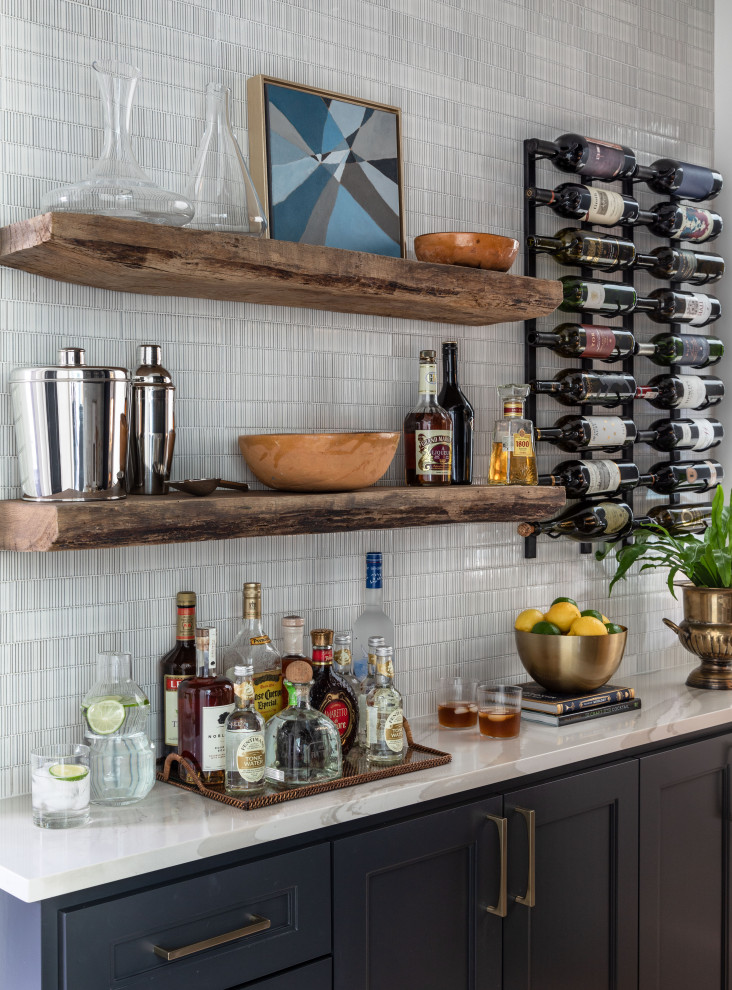 Mid-sized modern galley home bar in Houston with shaker cabinets, black cabinets, solid surface benchtops, white splashback, subway tile splashback, travertine floors, beige floor and white benchtop.