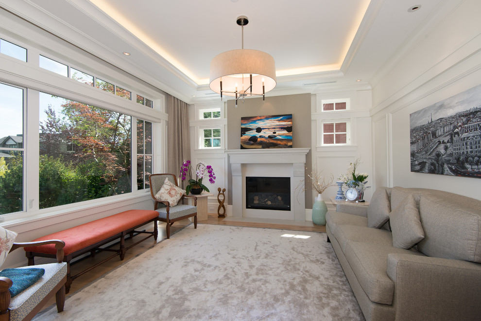 This is an example of a transitional formal enclosed living room in Vancouver with white walls, light hardwood floors, a standard fireplace and a concrete fireplace surround.