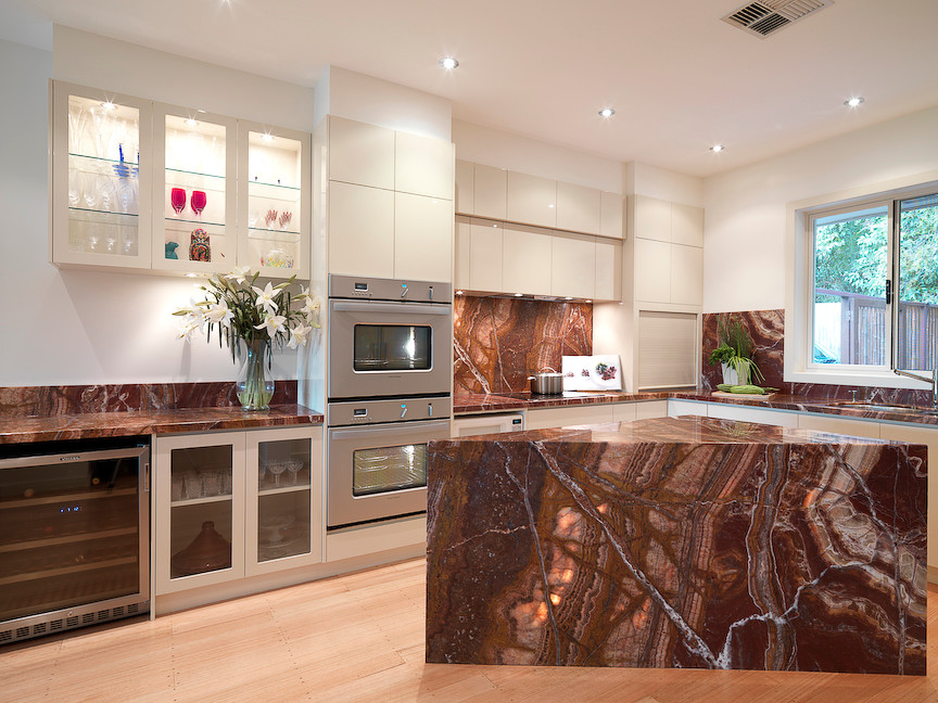 Expansive contemporary l-shaped eat-in kitchen in Melbourne with an undermount sink, glass-front cabinets, white cabinets, onyx benchtops, multi-coloured splashback, subway tile splashback, stainless steel appliances, medium hardwood floors and with island.