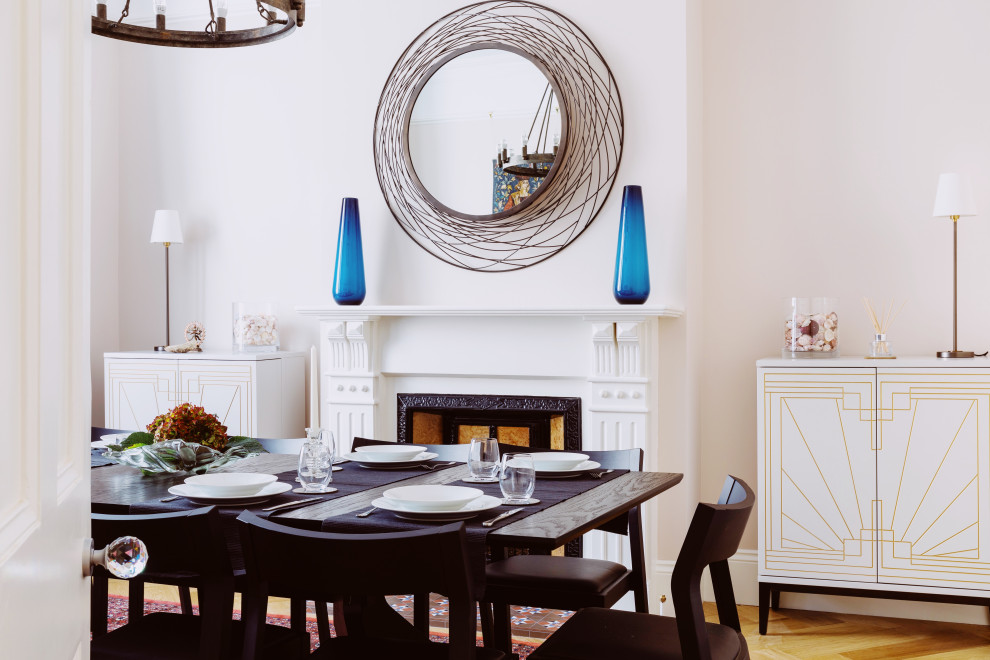 Design ideas for a large eclectic separate dining room in London with light hardwood floors, a standard fireplace, pink walls, a metal fireplace surround and beige floor.