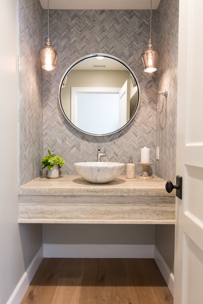 Inspiration for a small beach style powder room in Orange County with beige tile, gray tile, mosaic tile, light hardwood floors, a vessel sink, travertine benchtops, grey walls and beige floor.