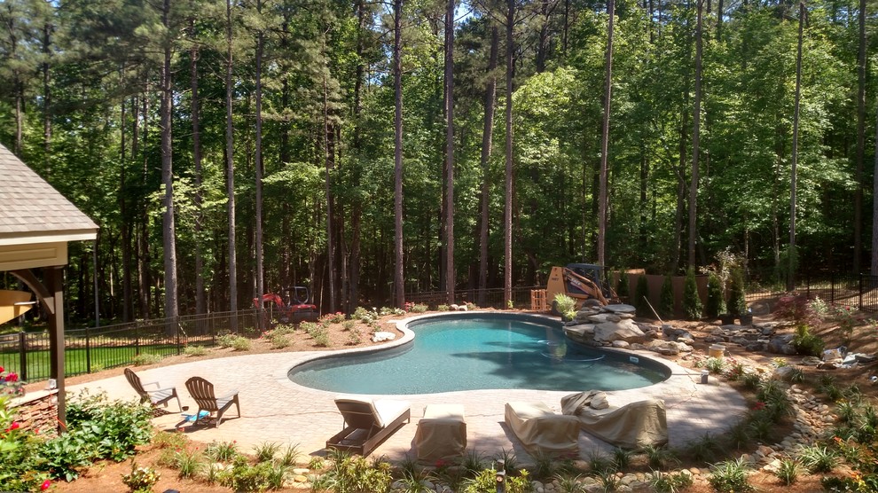 Large transitional backyard concrete paver and custom-shaped natural pool fountain photo in Raleigh