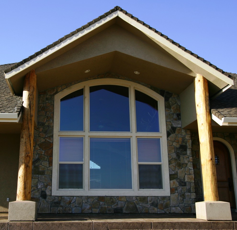 Photo of a mid-sized country two-storey stucco brown exterior in Other with a gable roof.