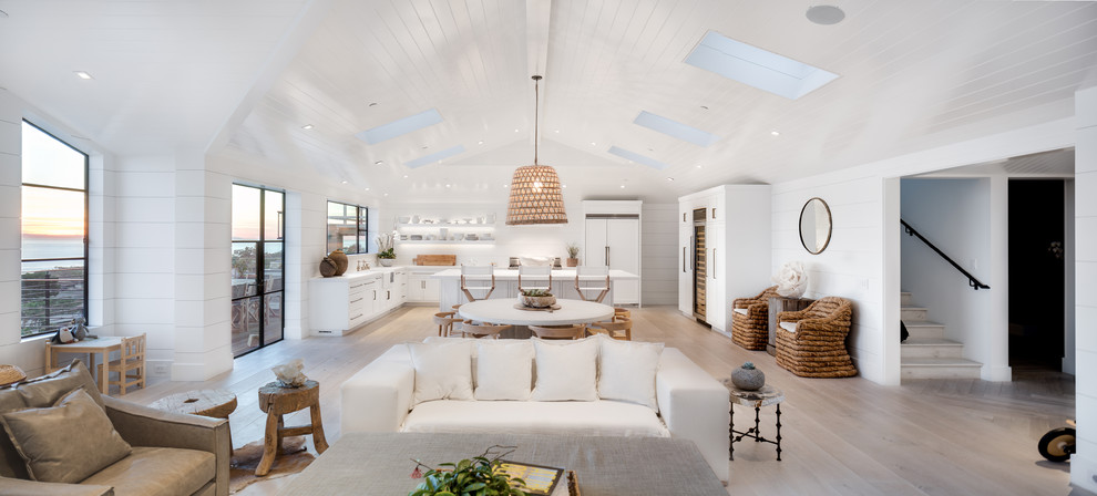 This is an example of a large beach style open concept living room in Orange County with white walls, light hardwood floors, a stone fireplace surround, a ribbon fireplace, a wall-mounted tv, beige floor, vaulted, wood and planked wall panelling.