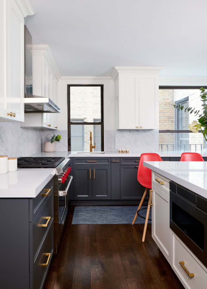 Photo of a large transitional l-shaped kitchen in New York with an undermount sink, shaker cabinets, black cabinets, grey splashback, black appliances, medium hardwood floors, with island, brown floor and white benchtop.