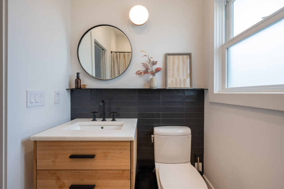 Cette image montre une petite salle de bain traditionnelle en bois clair avec un placard à porte plane, une baignoire en alcôve, un combiné douche/baignoire, WC séparés, un carrelage noir et blanc, des carreaux de porcelaine, un mur blanc, un sol en carrelage de céramique, un lavabo encastré, un plan de toilette en quartz modifié, un sol beige, une cabine de douche avec un rideau, un plan de toilette blanc, une niche, meuble simple vasque et meuble-lavabo suspendu.