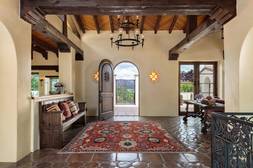 This is an example of a large mediterranean foyer in Miami with beige walls, a single front door, a dark wood front door, brown floor and ceramic floors.