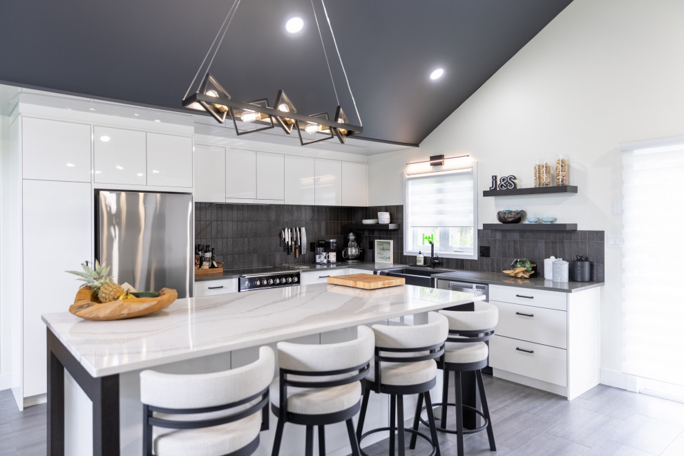 Photo of a mid-sized contemporary l-shaped open plan kitchen in Ottawa with a double-bowl sink, flat-panel cabinets, white cabinets, quartz benchtops, black splashback, porcelain splashback, stainless steel appliances, porcelain floors, with island, grey floor, white benchtop and vaulted.