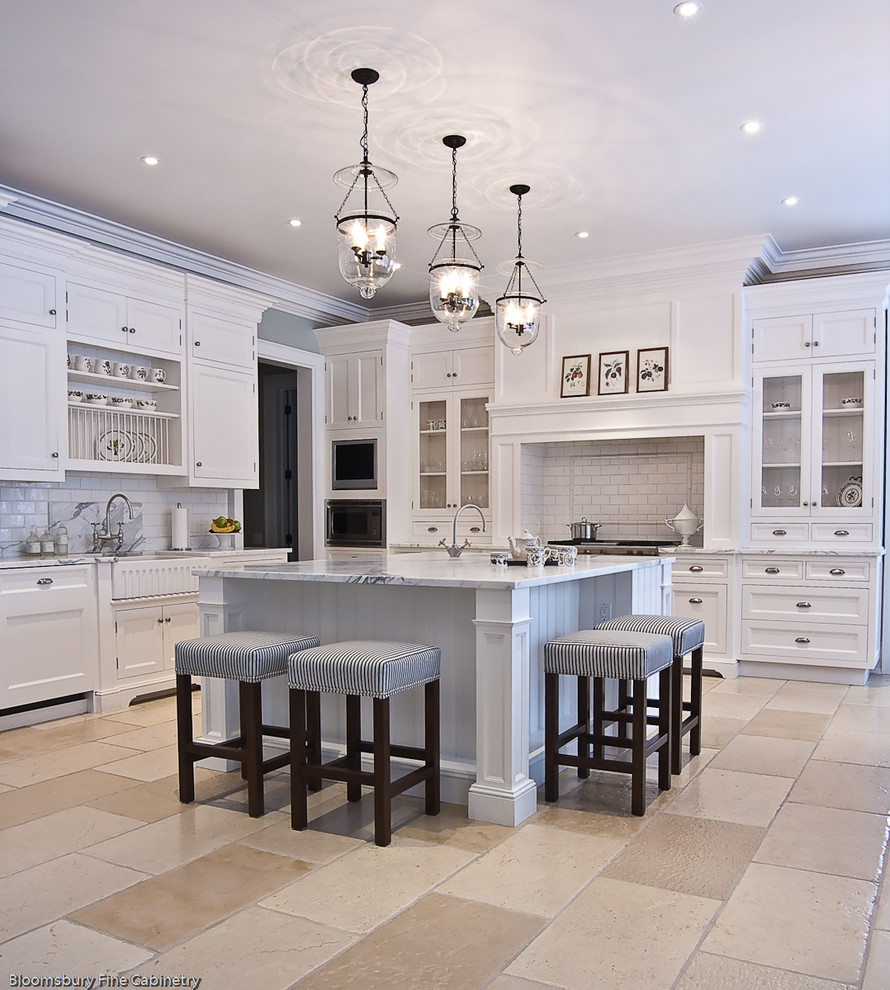 Design ideas for a large transitional u-shaped open plan kitchen in Toronto with a farmhouse sink, shaker cabinets, white cabinets, marble benchtops, white splashback, subway tile splashback, stainless steel appliances, limestone floors, with island and beige floor.