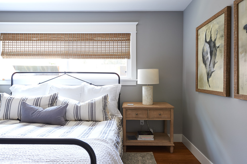 Large country guest bedroom in San Diego with grey walls, medium hardwood floors and brown floor.