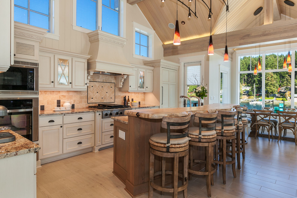 Photo of a beach style eat-in kitchen in Seattle with marble benchtops, beige splashback and stainless steel appliances.
