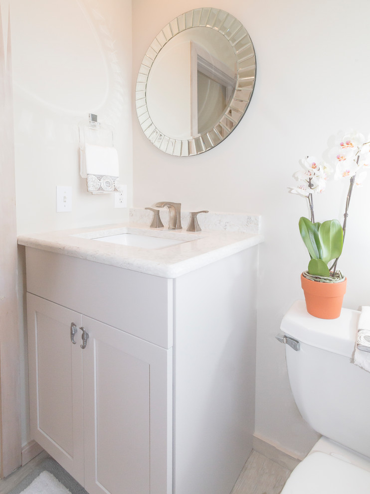Small transitional powder room in New York with flat-panel cabinets, white cabinets, beige walls, ceramic floors, an integrated sink, granite benchtops and beige floor.