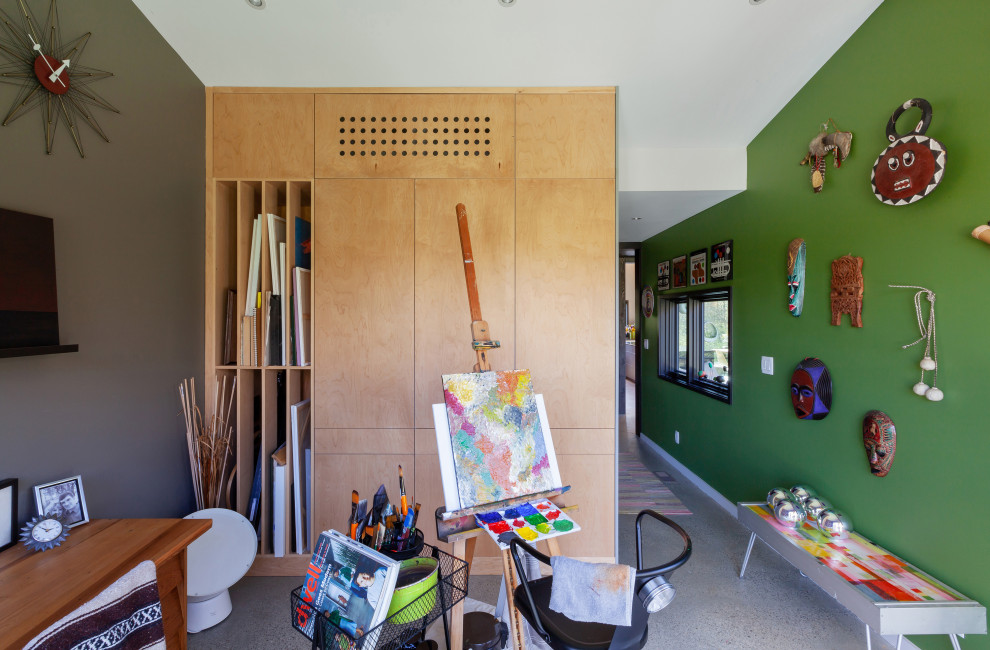 Inredning av ett modernt mellanstort hemmastudio, med gröna väggar, betonggolv, ett fristående skrivbord och grått golv