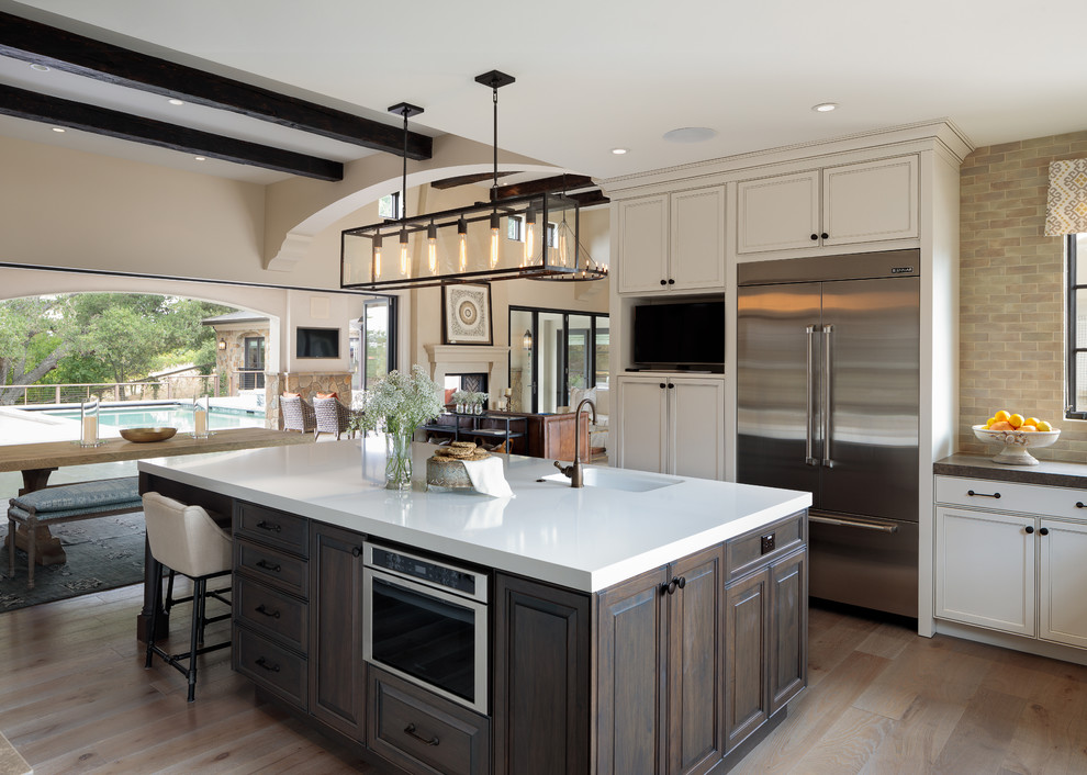 Photo of a large traditional kitchen in San Francisco with a single-bowl sink, recessed-panel cabinets, beige cabinets, beige splashback, stainless steel appliances, light hardwood floors, with island and beige floor.