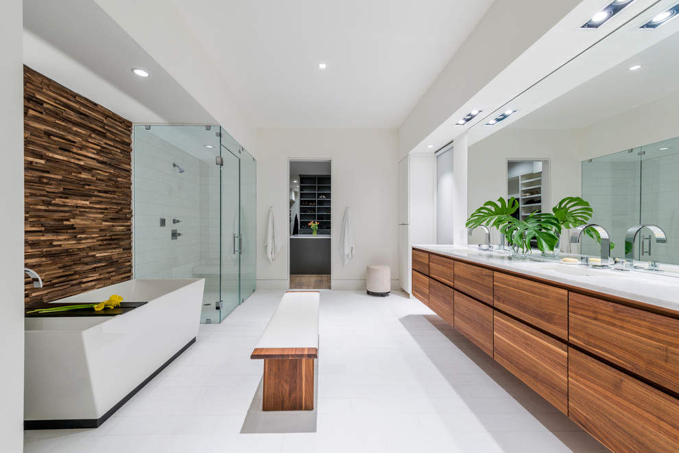 This is an example of a mid-sized contemporary master bathroom in Dallas with flat-panel cabinets, dark wood cabinets, a freestanding tub, a corner shower, white tile, white walls, an undermount sink, white floor, a hinged shower door, a one-piece toilet, porcelain tile, porcelain floors and engineered quartz benchtops.