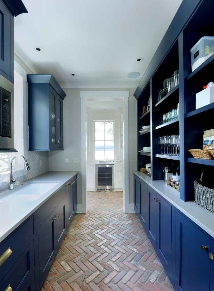 Mid-sized transitional galley kitchen pantry in Grand Rapids with recessed-panel cabinets, blue cabinets, granite benchtops, white splashback, shiplap splashback, stainless steel appliances, brick floors, red floor, white benchtop and no island.