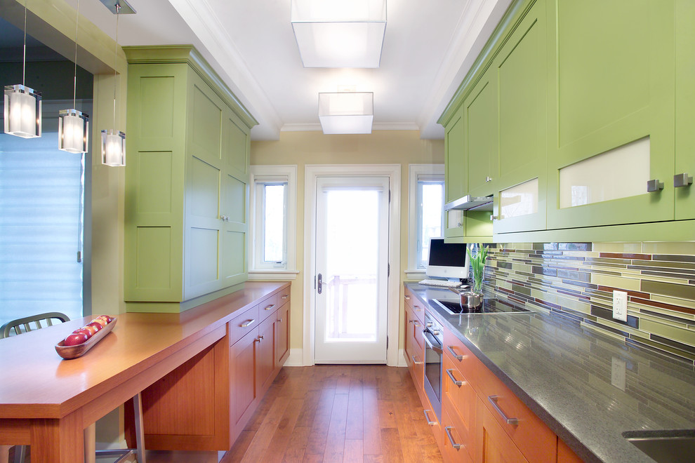 Eklektisk inredning av ett kök, med en enkel diskho, släta luckor, gröna skåp, bänkskiva i kvartsit, rosa stänkskydd, stänkskydd i glaskakel, rostfria vitvaror och mörkt trägolv
