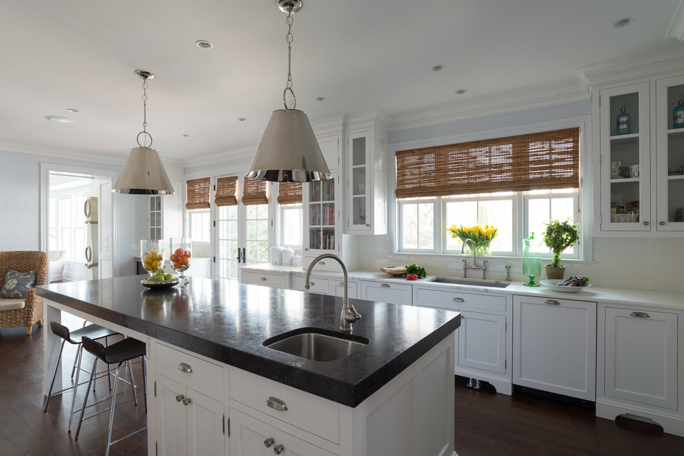 This is an example of a traditional eat-in kitchen in New York with white cabinets, white splashback, subway tile splashback, dark hardwood floors and with island.