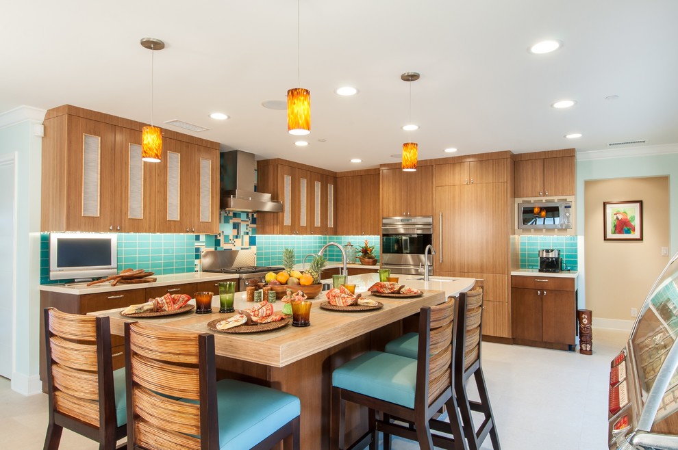 Photo of a tropical l-shaped open plan kitchen in Los Angeles with an undermount sink, flat-panel cabinets, medium wood cabinets, blue splashback, stainless steel appliances, with island and beige floor.