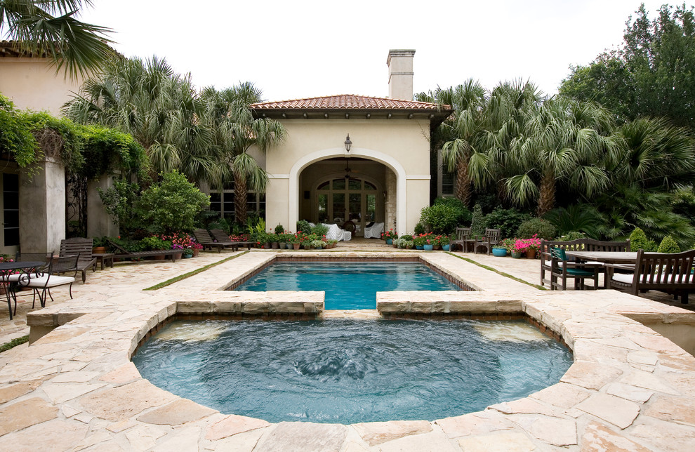 Mid-sized tuscan backyard stone and rectangular lap hot tub photo in Austin