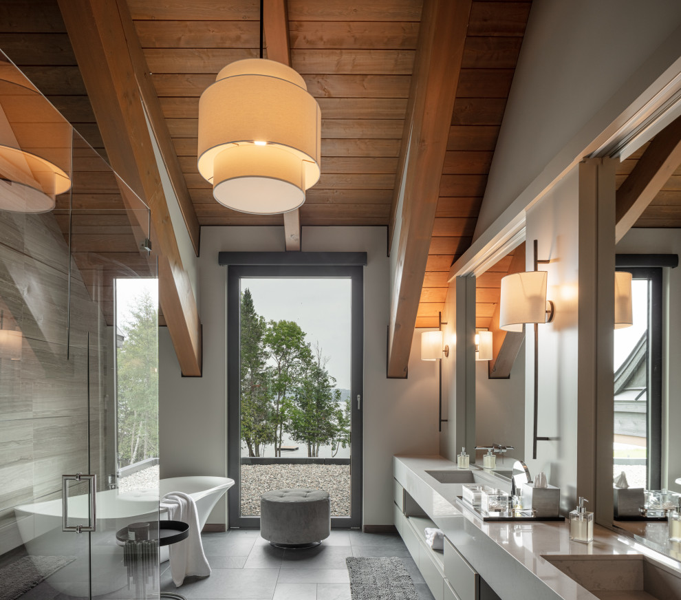 Geräumiges Modernes Badezimmer En Suite mit weißen Schränken, freistehender Badewanne, grauer Wandfarbe, grauem Boden, weißer Waschtischplatte und eingebautem Waschtisch in Montreal