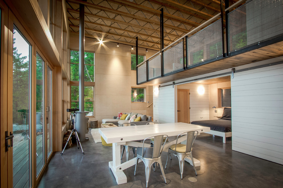 This is an example of a mid-sized industrial open plan dining in Seattle with beige walls, concrete floors, a hanging fireplace, a metal fireplace surround and grey floor.