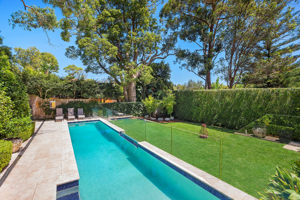 Photo of a mid-sized transitional backyard rectangular lap pool in Sydney with natural stone pavers.