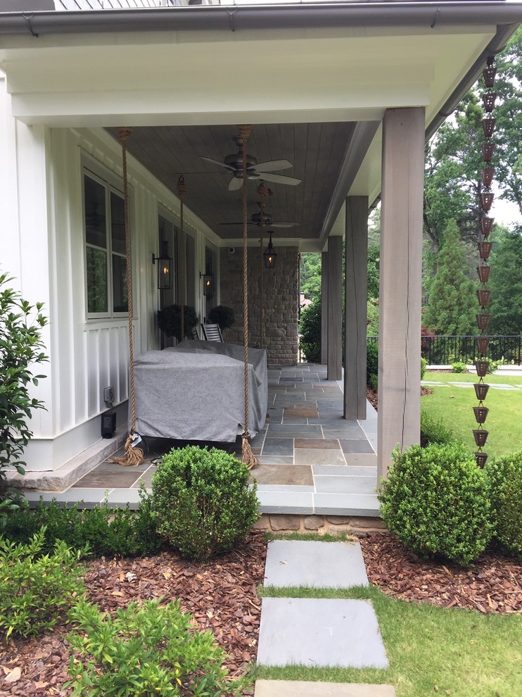Design ideas for a mid-sized country front yard verandah in Atlanta with natural stone pavers and a roof extension.