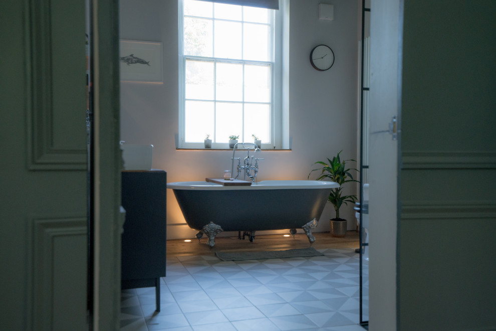 Exemple d'une grande salle de bain victorienne pour enfant avec une baignoire indépendante, un mur blanc, un sol marron, des portes de placard bleues, un sol en carrelage de céramique, meuble double vasque et meuble-lavabo sur pied.
