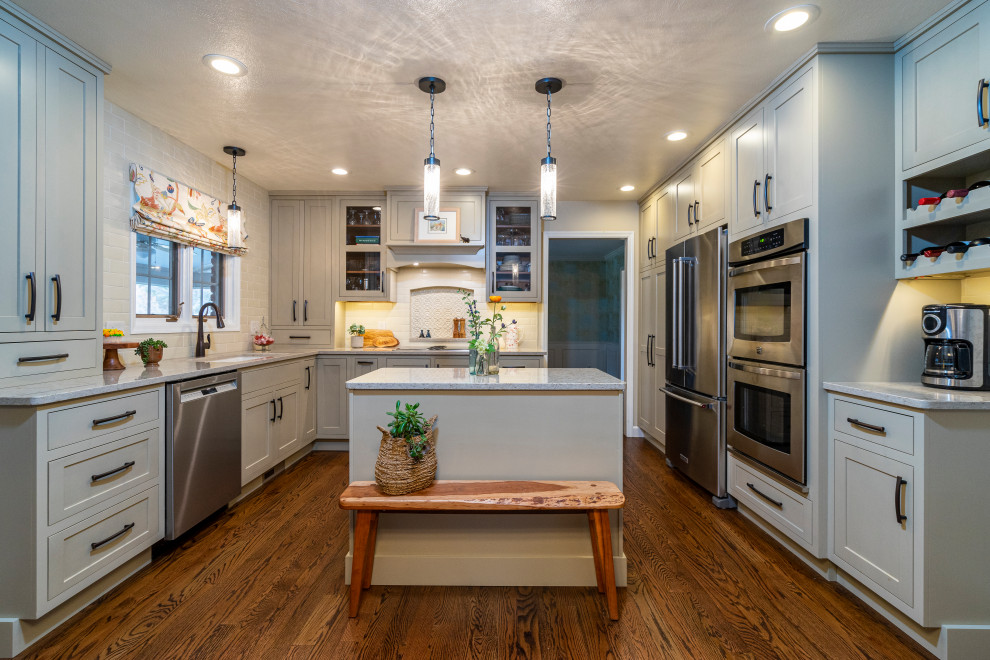 Photo of a mid-sized country u-shaped separate kitchen in Other with a single-bowl sink, recessed-panel cabinets, green cabinets, quartz benchtops, white splashback, ceramic splashback, stainless steel appliances, medium hardwood floors, with island, brown floor and beige benchtop.