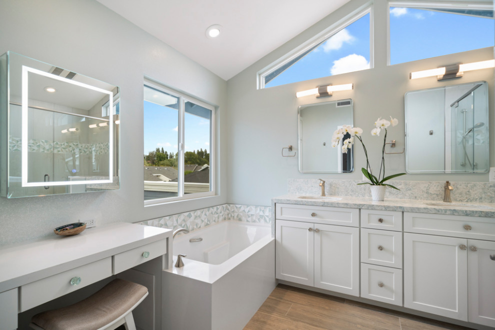 Design ideas for a mid-sized beach style bathroom in Orange County with shaker cabinets, white cabinets, a drop-in tub, a one-piece toilet, multi-coloured tile, glass tile, blue walls, wood-look tile, an undermount sink, engineered quartz benchtops, brown floor, a hinged shower door, multi-coloured benchtops and a built-in vanity.