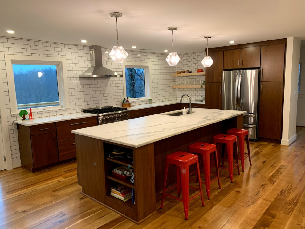 Inspiration for a large mid-century modern l-shaped light wood floor and brown floor enclosed kitchen remodel in Louisville with an undermount sink, flat-panel cabinets, dark wood cabinets, quartz countertops, white backsplash, subway tile backsplash, stainless steel appliances, an island and white countertops