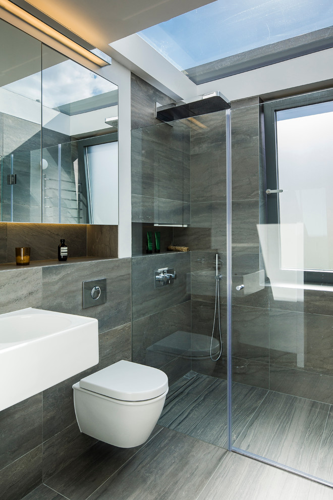 Design ideas for a contemporary bathroom in London with a curbless shower, a wall-mount toilet and gray tile.