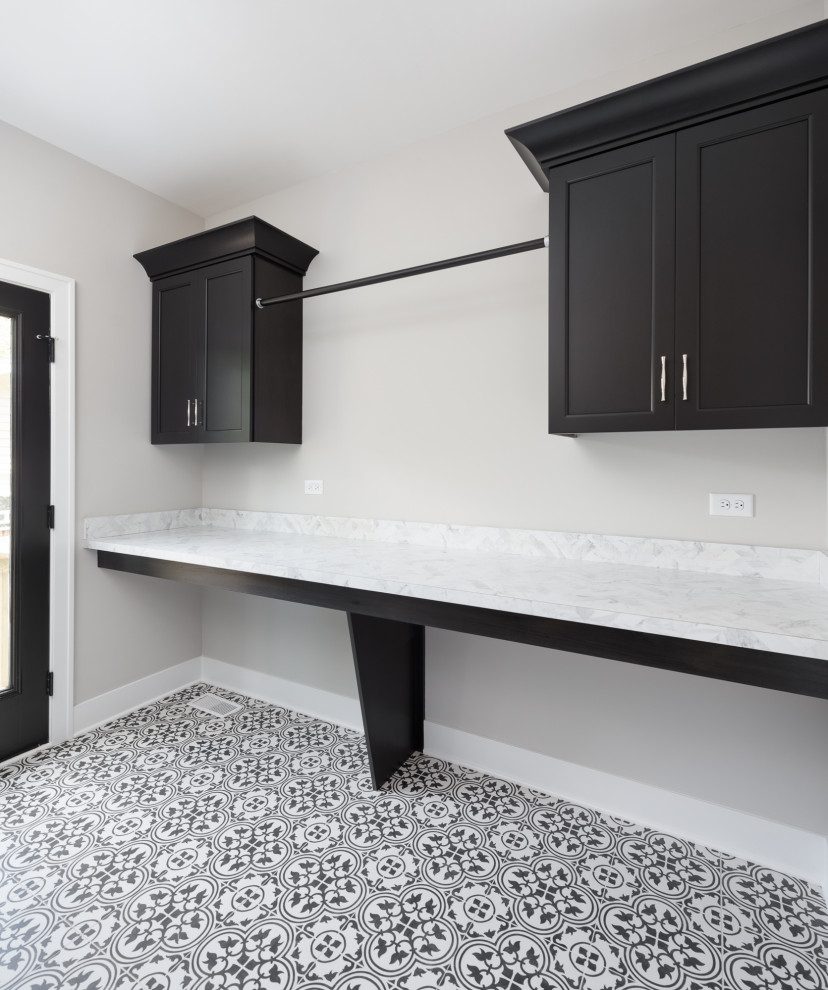 Inspiration for a large country galley dedicated laundry room in Chicago with a drop-in sink, recessed-panel cabinets, black cabinets, grey walls, porcelain floors, a side-by-side washer and dryer and multi-coloured floor.