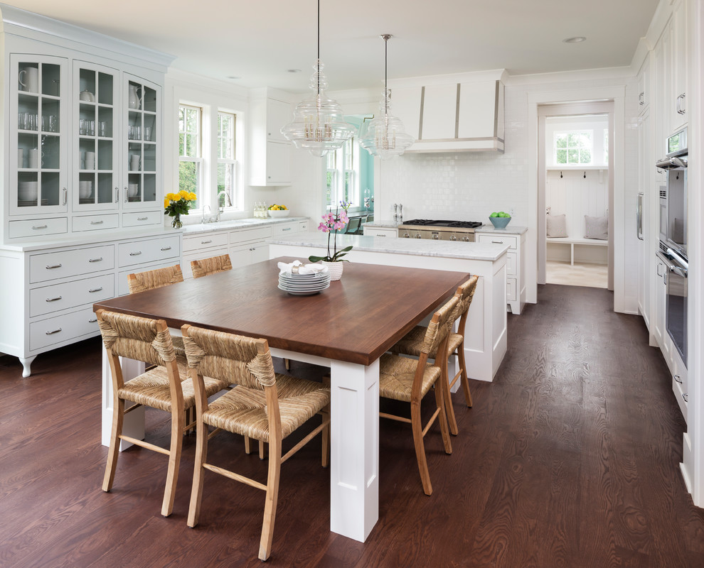 Design ideas for a large beach style eat-in kitchen in Minneapolis with white cabinets, marble benchtops, white splashback, ceramic splashback, stainless steel appliances, dark hardwood floors, with island, brown floor, glass-front cabinets and grey benchtop.