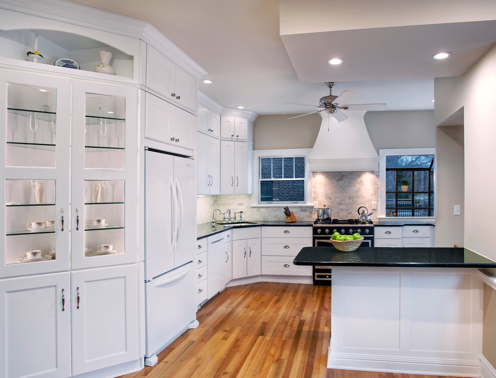 Eat-in kitchen - small transitional medium tone wood floor eat-in kitchen idea with recessed-panel cabinets, a peninsula, an undermount sink, white cabinets, granite countertops, gray backsplash, stone tile backsplash and white appliances